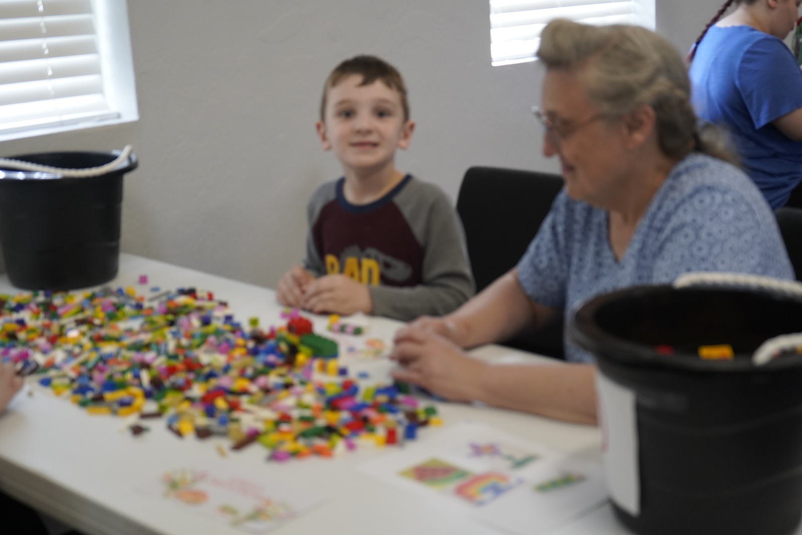 A smiling child creating alongside a caring adult at Refuge Church