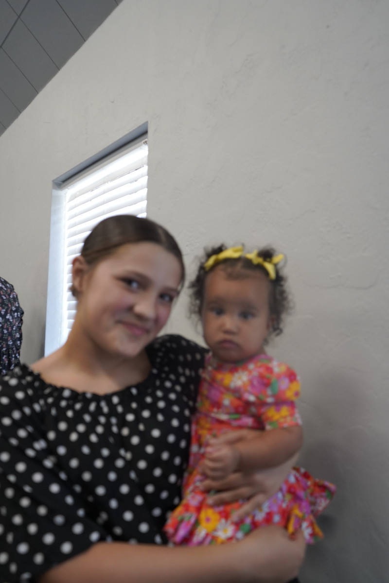 A smiling young adult holding a baby at Refuge Church